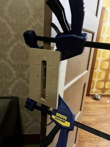Door frame being prepared for a new lock with clamps holding the jig in place